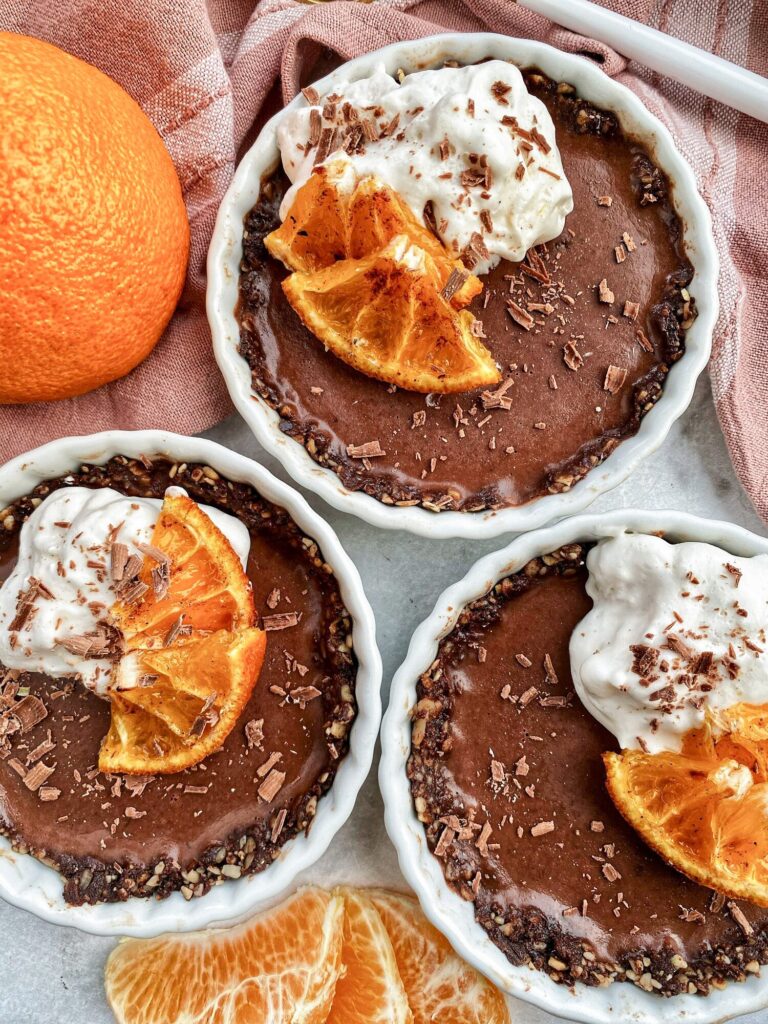 Three small chocolate ganache tarts topped with whipped cream.