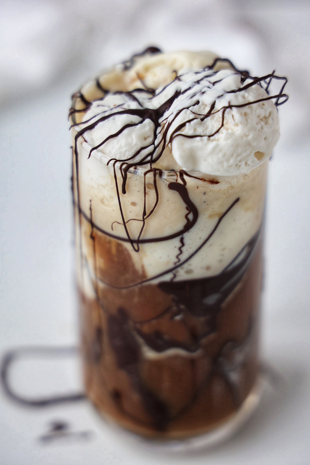 A glass with ice cream, cold brew, chocolate drizzle, and topped with whipped cream.