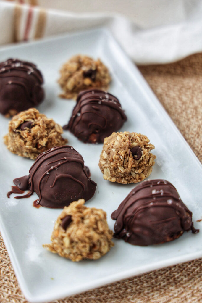 No bake peanut butter oatmeal balls, covered in chocolate, on a white plate.