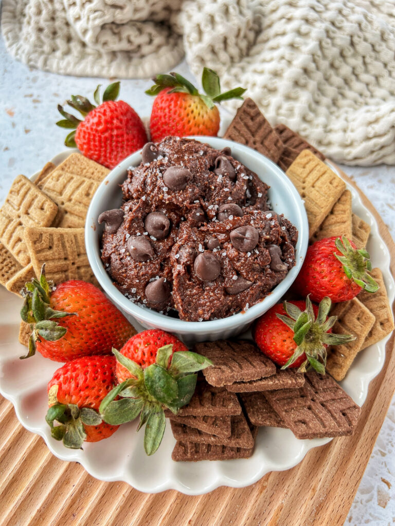 A big plate with cookies, fruit, and graham crackers with a bowl of brownie batter dip.