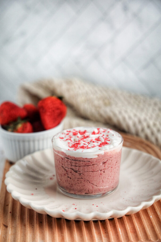 Jar of strawberry mousse topped with coconut whipped topping.