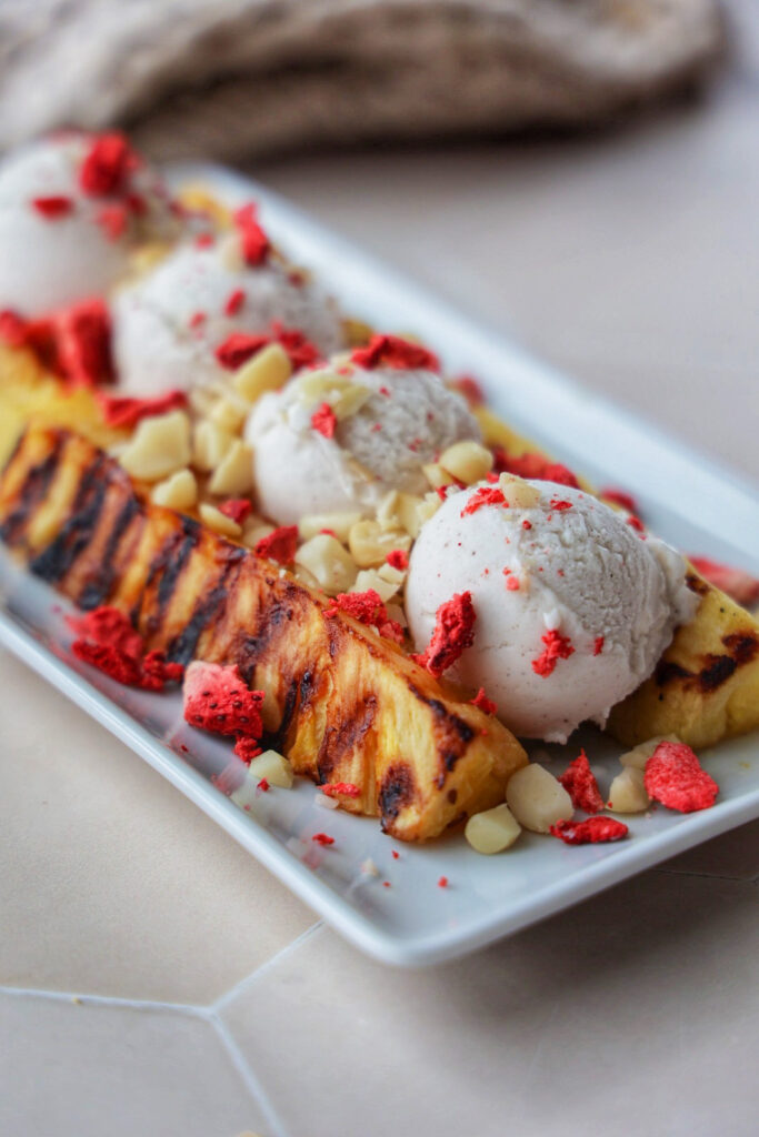 Grilled pineapple split topped with ice cream and macadamia nuts.