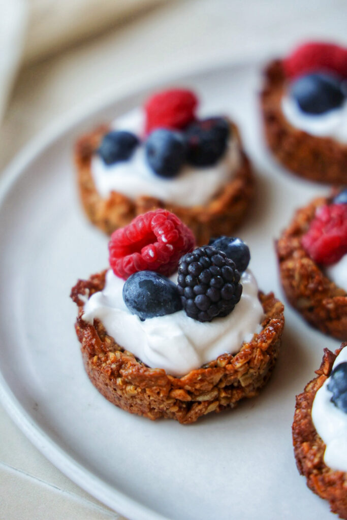 A plate of yogurt granola cups topped with berries.