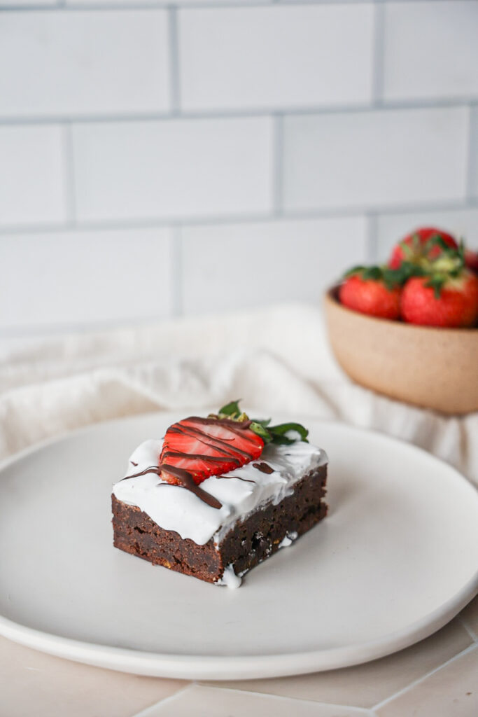 Fudgy paleo brownies with whipped cream and strawberries.